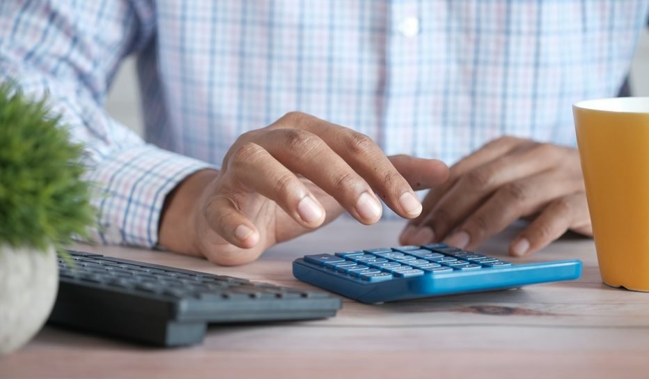 Hands using a calculator for income tax and GST computation